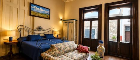 A bedroom with a bed, a sofa, a dresser, and a window with a view of buildings.