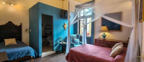 A bedroom with a bed, a chair, a nightstand, and a window with a view.