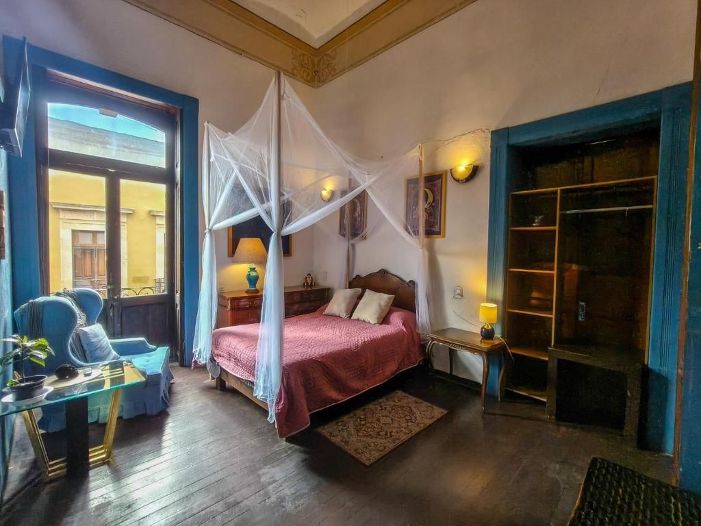 Una habitación con cama, mesita de noche, lámpara y ventana con cortinas.