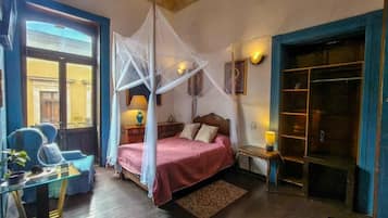 Una habitación con cama, mesita de noche, lámpara y ventana con cortinas.