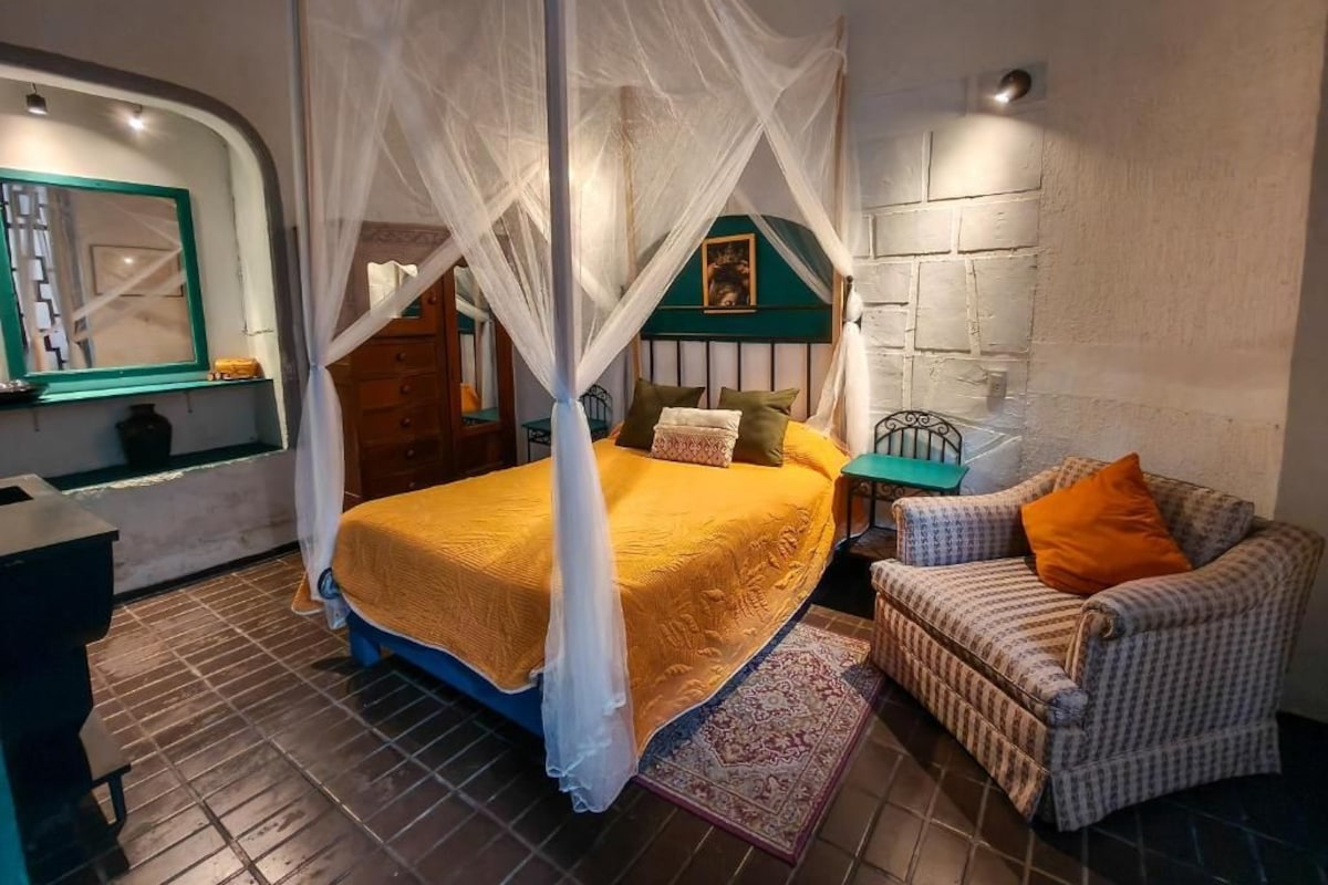 Une chambre à coucher comprenant un lit, une chaise, une table de chevet et une étagère fixée au mur.