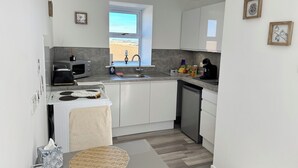 A modern kitchen with white cabinets, a built-in oven, a microwave, and a coffee maker.