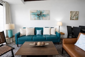 A living room with a teal sofa, a brown leather couch, a wooden coffee table with decorative items, and two lamps. - Splash and Stay at Kimberling Crossing (Kimberling City)