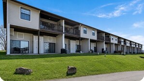 Un edificio de apartamentos de varios pisos con balcones, ventanas amplias y un césped bien cuidado.