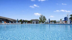 A clear swimming pool with lounge chairs and a water slide.