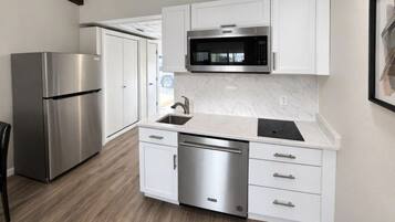 A modern kitchen with stainless steel appliances, white cabinetry, and a marble countertop.