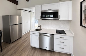 A modern kitchen with stainless steel appliances, white cabinetry, and a marble countertop. - Happy Harbor at Kimberling Crossing (Kimberling City)