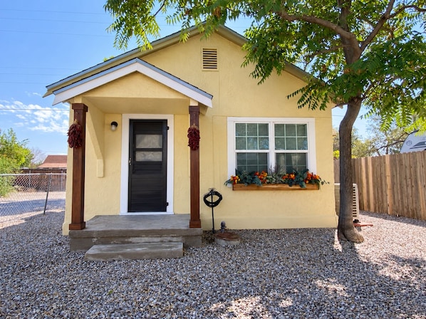 A single-story house with a front porch, a black front door, and a window with a flower box.