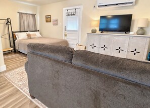 A living room with a sofa, a bed, a television, and a cabinet.