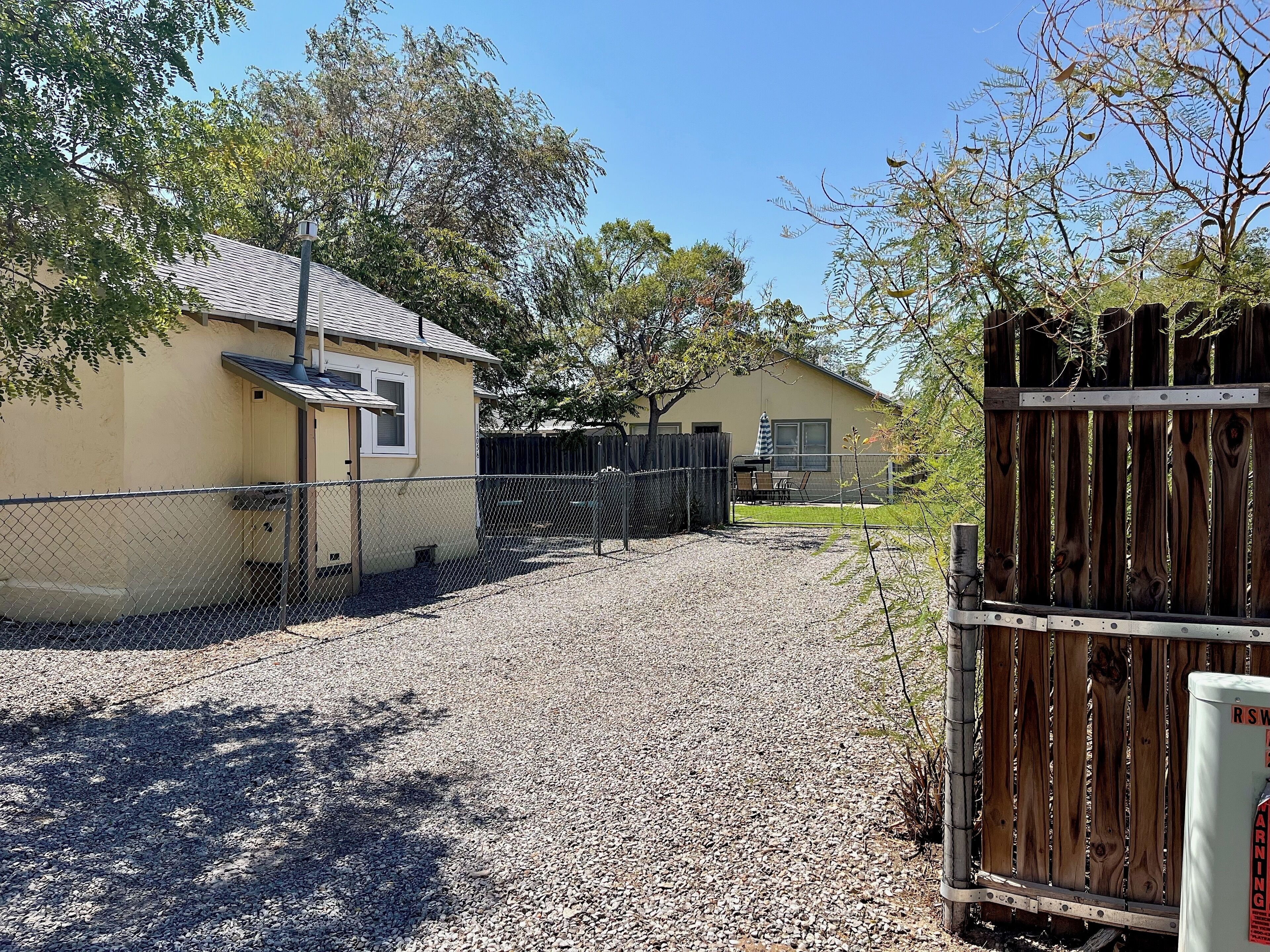 A fenced property with a gravel driveway leading to a building with a metal roof.