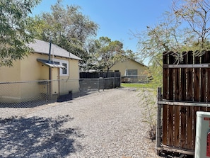 A fenced property with a gravel driveway leading to a building with a metal roof.