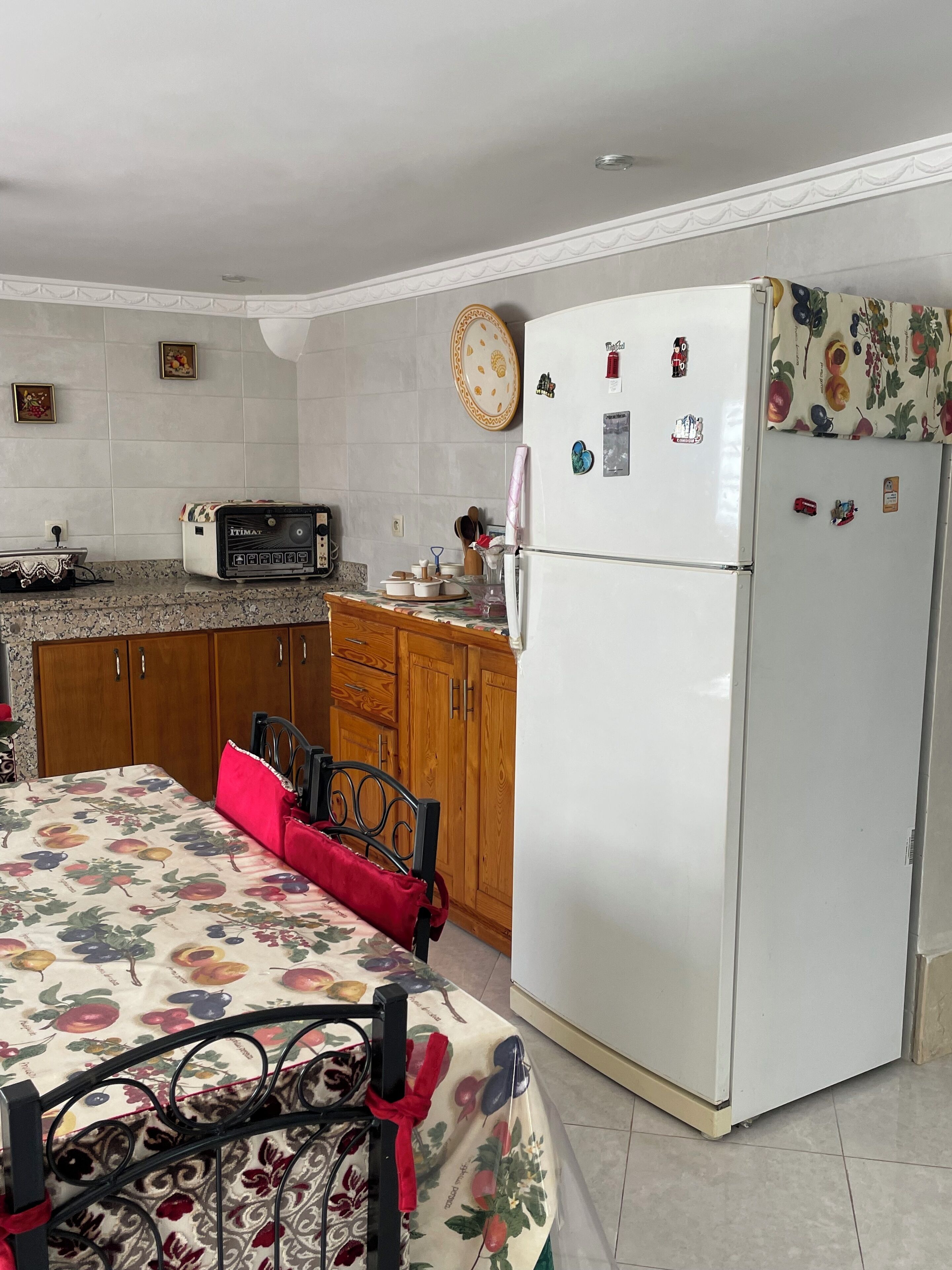 A kitchen with a refrigerator, microwave, and wooden cabinets.