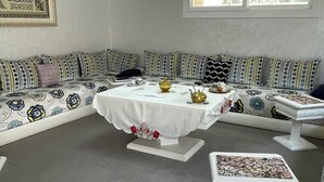 A room with a round table, a sofa with patterned cushions, a chandelier, and a framed picture on the wall. - House (level1) 10 mn beach Mehdia Kénitra in magnificent villa peaceful calm (Kénitra)
