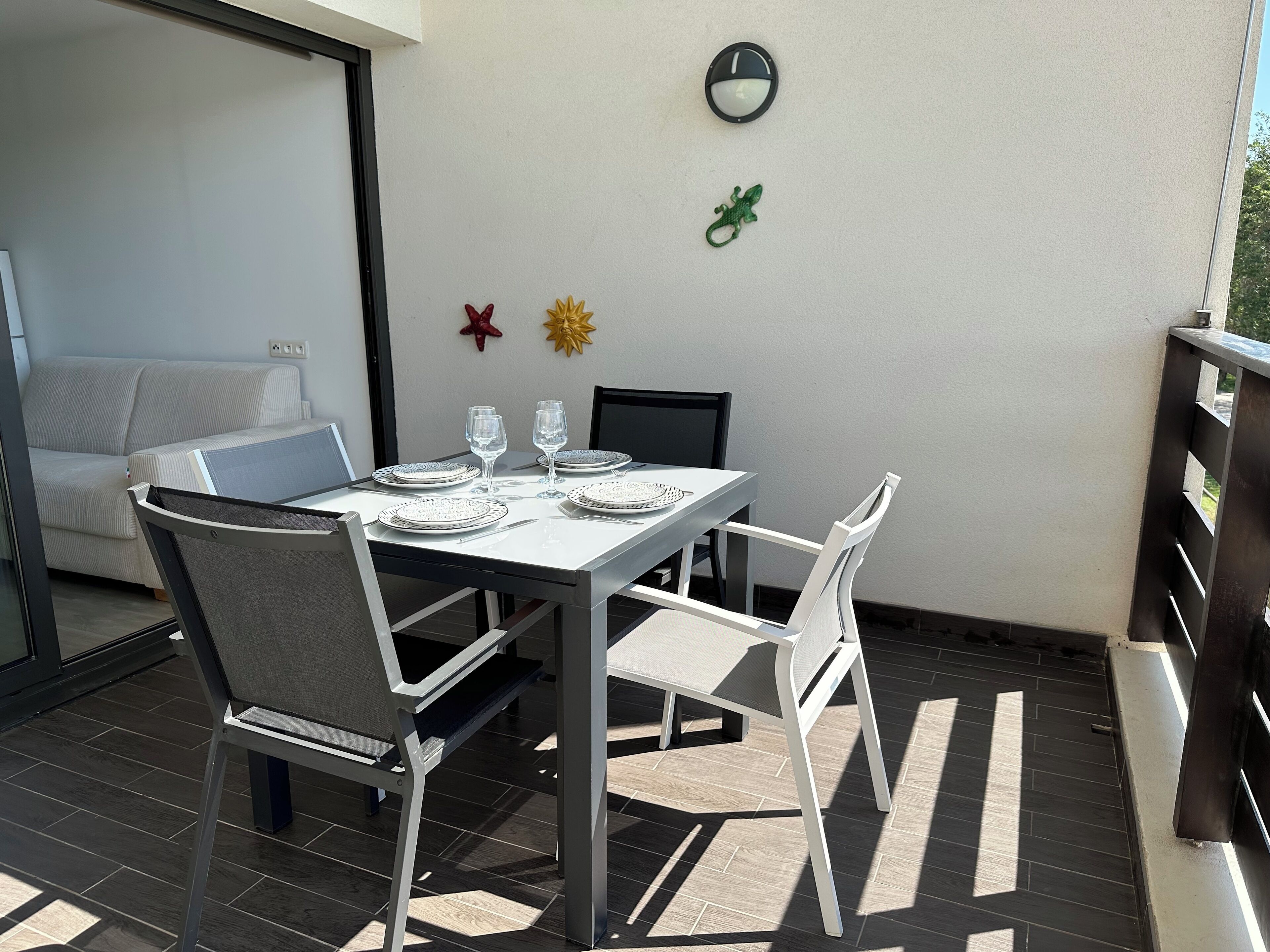 A dining area with a table set for two, two chairs, and a small decorative wall piece.