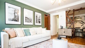 A living room with a white sofa, a patterned rug, and three framed black and white photographs on the wall.