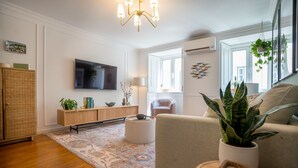 A living room with a large flat-screen TV, a sofa, a coffee table, and a patterned rug.