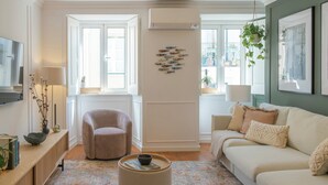 A modern living room with a beige sofa, a round coffee table, and a decorative wall with fish art.