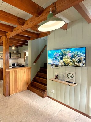 A kitchen with wooden beams, a microwave, and a sink.