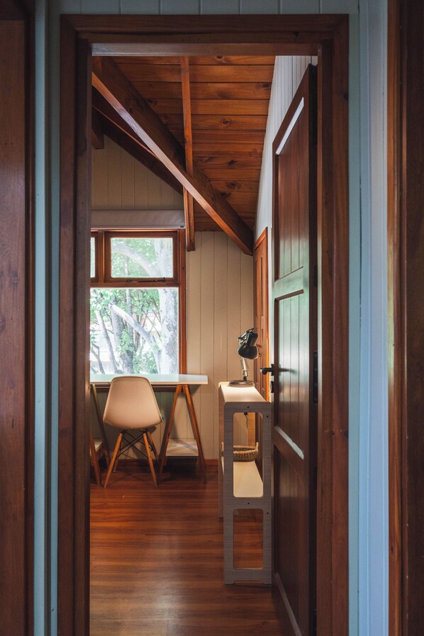 A wooden interior with a desk, chair, and window.