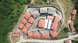 An aerial view of a large complex with multiple buildings, including a central structure with a large white facade and surrounding buildings with red roofs.