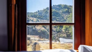 Una ventana con vista a un paisaje montañoso, una valla y un edificio a lo lejos.