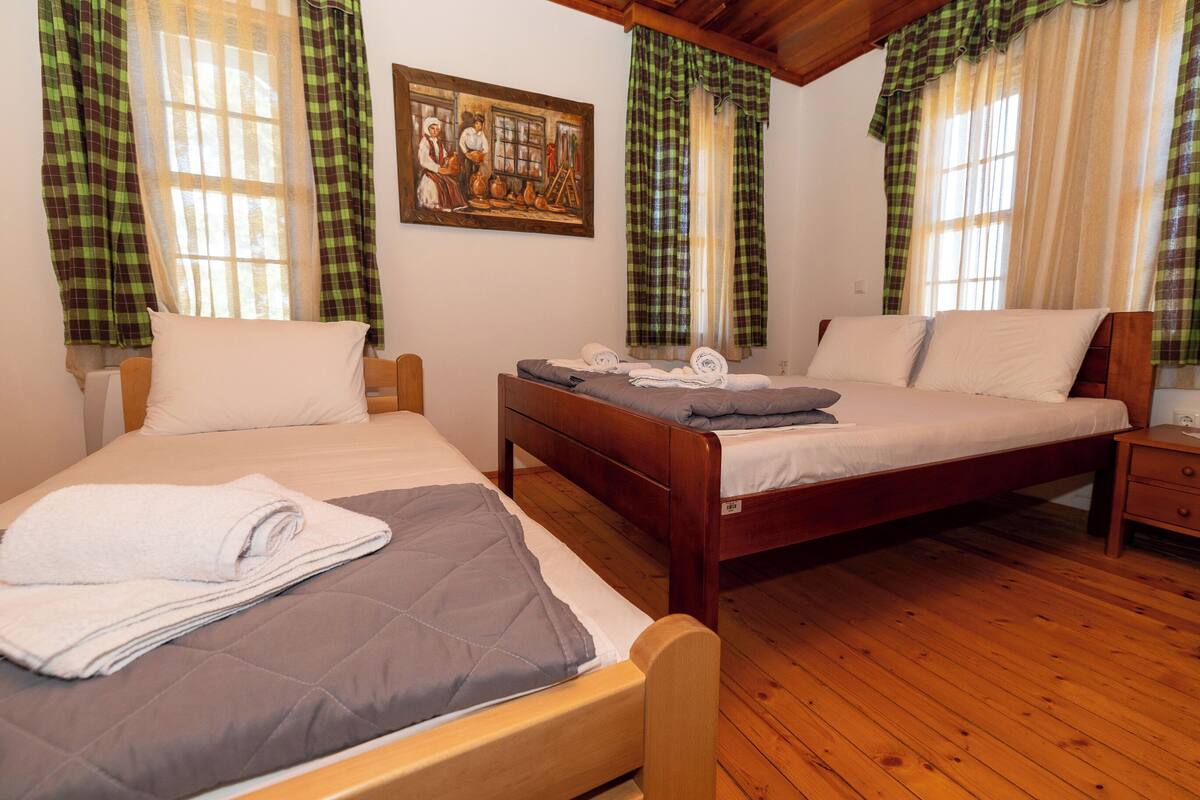 Une chambre avec deux lits, un plancher en bois et des rideaux à carreaux.