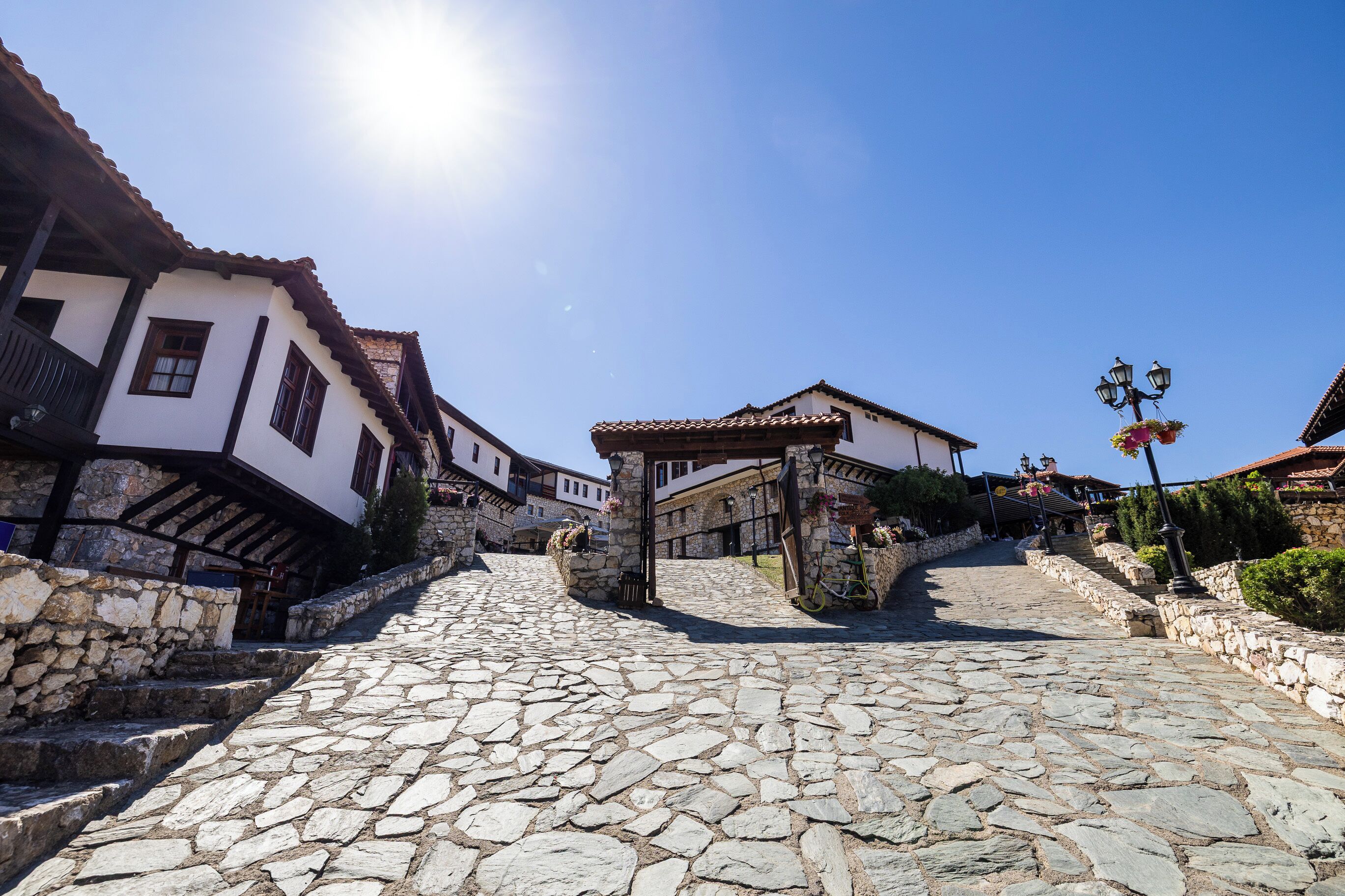 A cobblestone street leading to a stone building with a tiled roof.