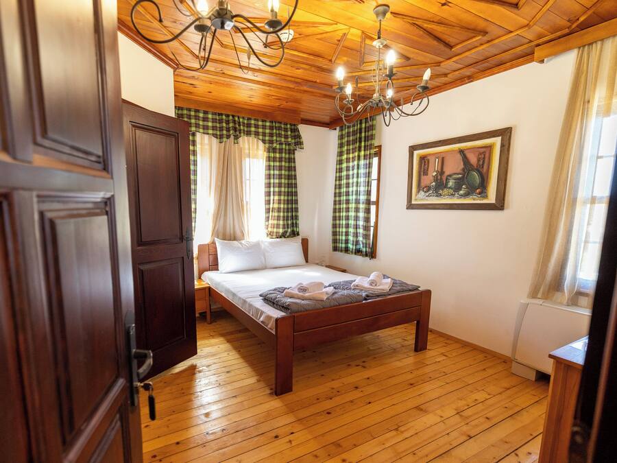 A wooden-paneled room with a bed, a chandelier, and a painting on the wall.