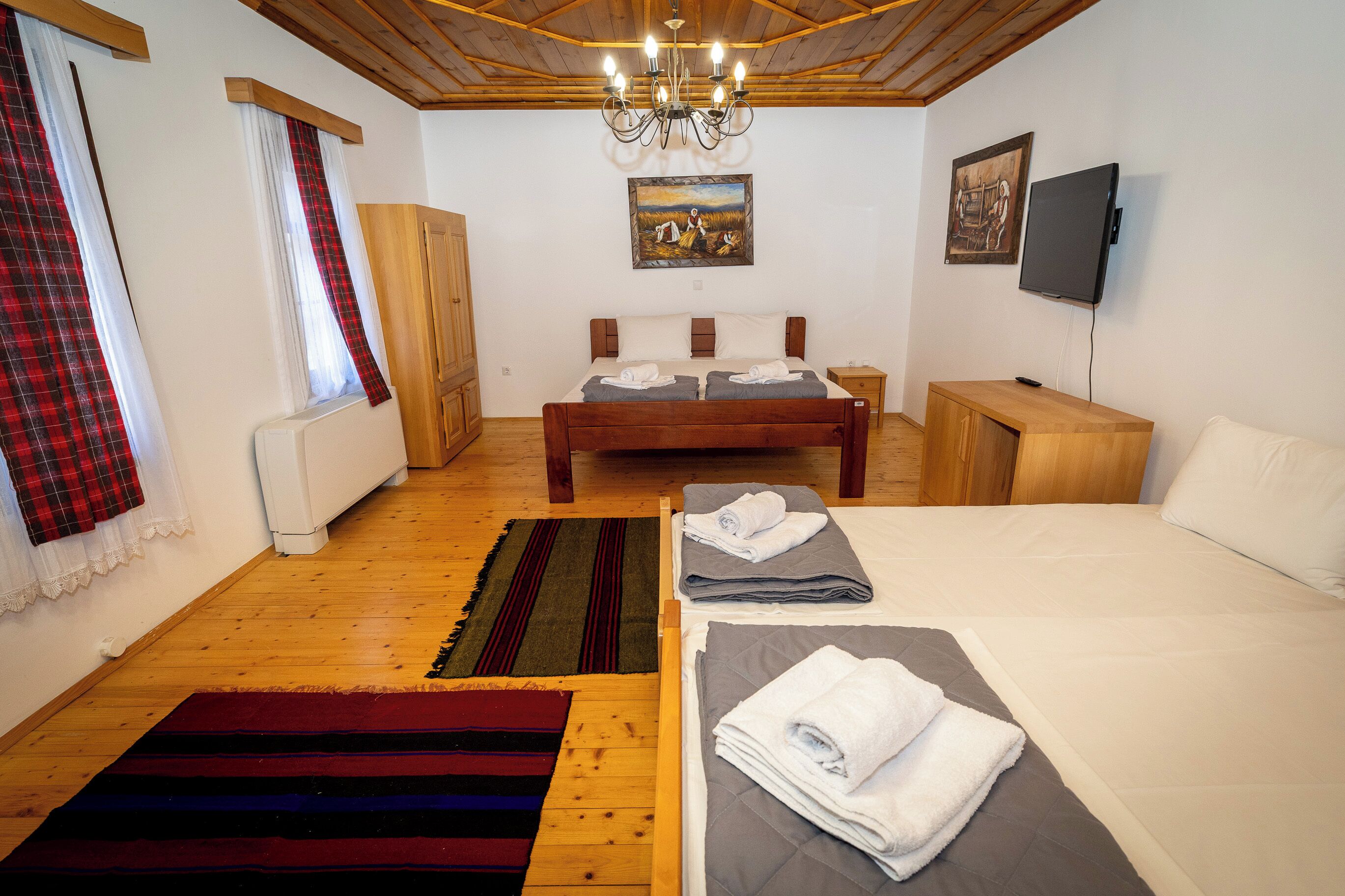 A bedroom with a wooden bed, a TV, and a painting on the wall.