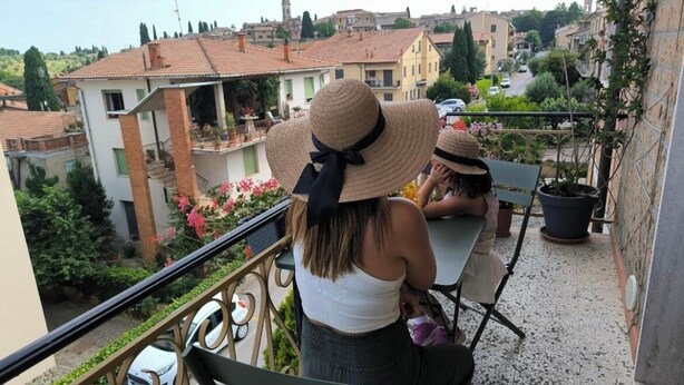 Un balcon donnant sur un quartier résidentiel, agrémenté d’une balustrade, d’un banc et de plantes en pot.