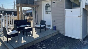 A covered outdoor seating area with two chairs and a table, a white door, and a garage labeled 'A'.