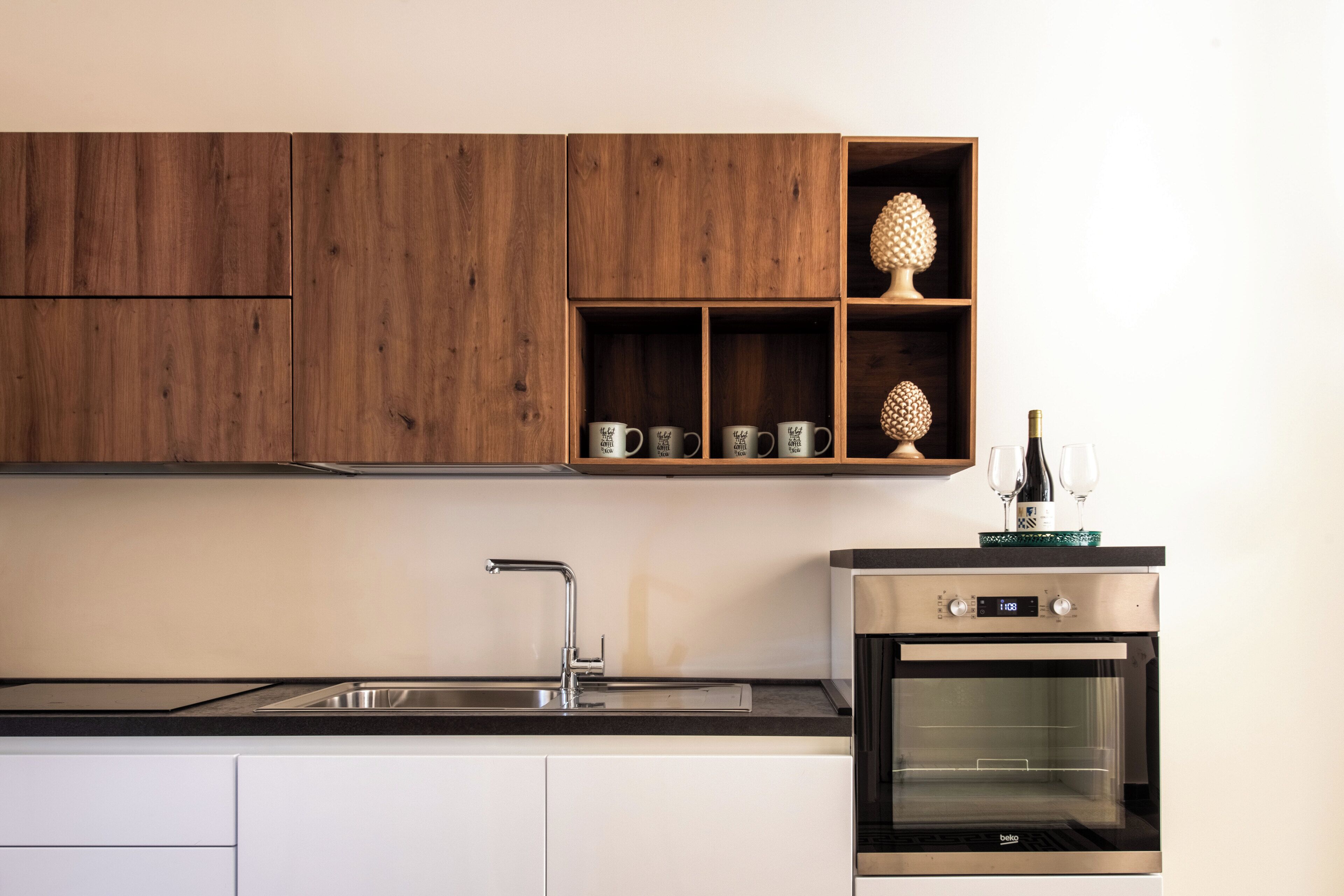 A kitchen with wooden cabinets, a stainless steel sink, and a built-in oven.