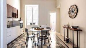 Una cocina moderna con una mesa redonda de comedor, sillas y una cafetera. Hay una ventana con vistas al exterior.
