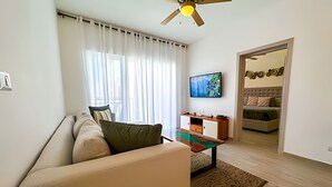 Een woonkamer met een bank, een salontafel, een televisie en een schilderij aan de muur.