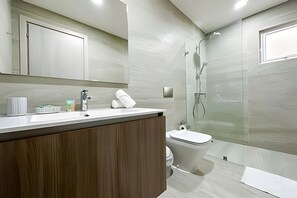 Ein modernes Badezimmer mit Waschtisch aus Holz, Toilette und einer Duschkabine.