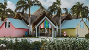 Un bâtiment aux couleurs vives, doté d’une entrée centrale et d’un toit de chaume.