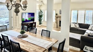 A spacious living room with a wooden dining table, black chairs, a fireplace, and a large TV. - Big 4-bedroom House close to Beach in San Clemente (San Clemente)