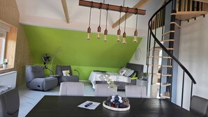 Uma sala de estar moderna com uma parede de destaque verde, teto de madeira e escada preta.