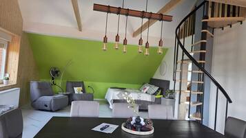 Un salon moderne avec un mur d’accent vert, un plafond en bois et un escalier noir.
