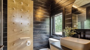 Ein modernes Badezimmer mit einer Holzwand, einer Toilette, einem Waschbecken und einem Fenster.