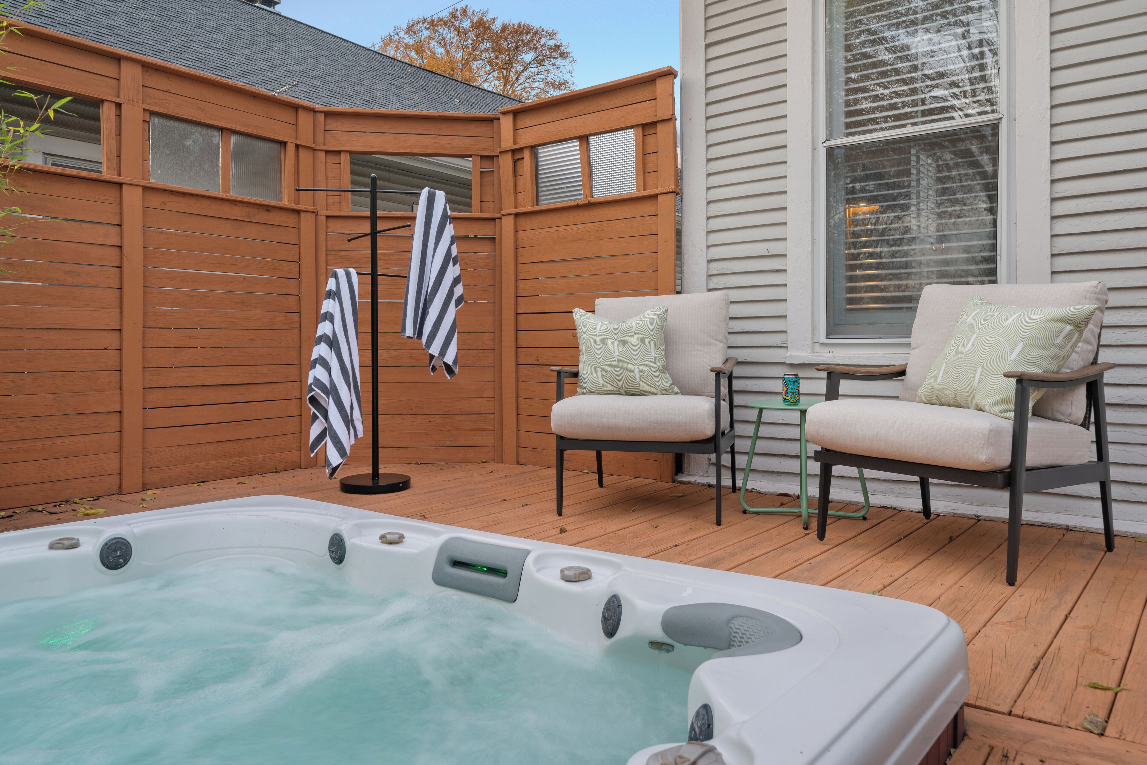 Een hottub in een houten terrasgedeelte met twee stoelen en een kleine tafel.