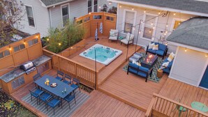 A backyard deck with a hot tub, outdoor seating, and a barbecue area. - Hot Tub & Game Room~ Private Cooper-Young Bungalow -Fire Pit - Large Yard (Memphis)