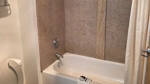 Een badkamer met een bad, toilet en douchegordijn.