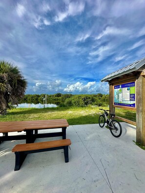 Ein Picknicktisch und ein Fahrrad in der Nähe einer Holzhütte mit einer Karte und einem Infostand.