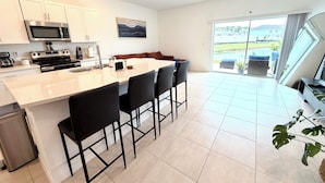 Una cocina moderna con una isla central, muebles blancos y electrodomésticos de acero inoxidable.