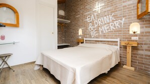 Ein gemütliches Schlafzimmer mit Backsteinwand, einem Bett, einem kleinen Tisch und einem Spiegel.