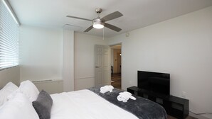 A bedroom with a bed, a ceiling fan, a TV, and a door leading to another room. - 2-bedroom apartment in Midtown Memphis with AC, fitness room (Memphis)
