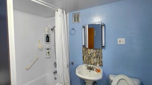 Un baño con bañera, lavamanos, inodoro y espejo.