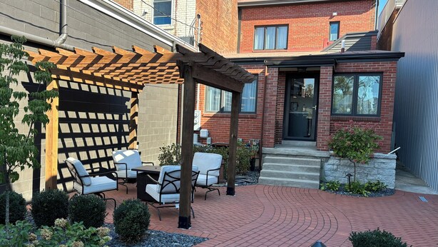 Un patio con mobiliario exterior, una pérgola y un sendero de ladrillos.