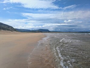 A beach with a sandy shore and gentle waves, with mountains in the background under a partly cloudy sky. - SEA CREST - Glamping Pod with fabulous sea views on the Wild Atantic Way Donegal (Donegal)